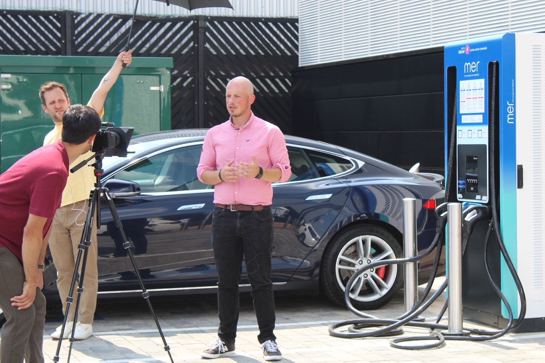 Giles Benbow presenting beside an electric vehicle charging unit